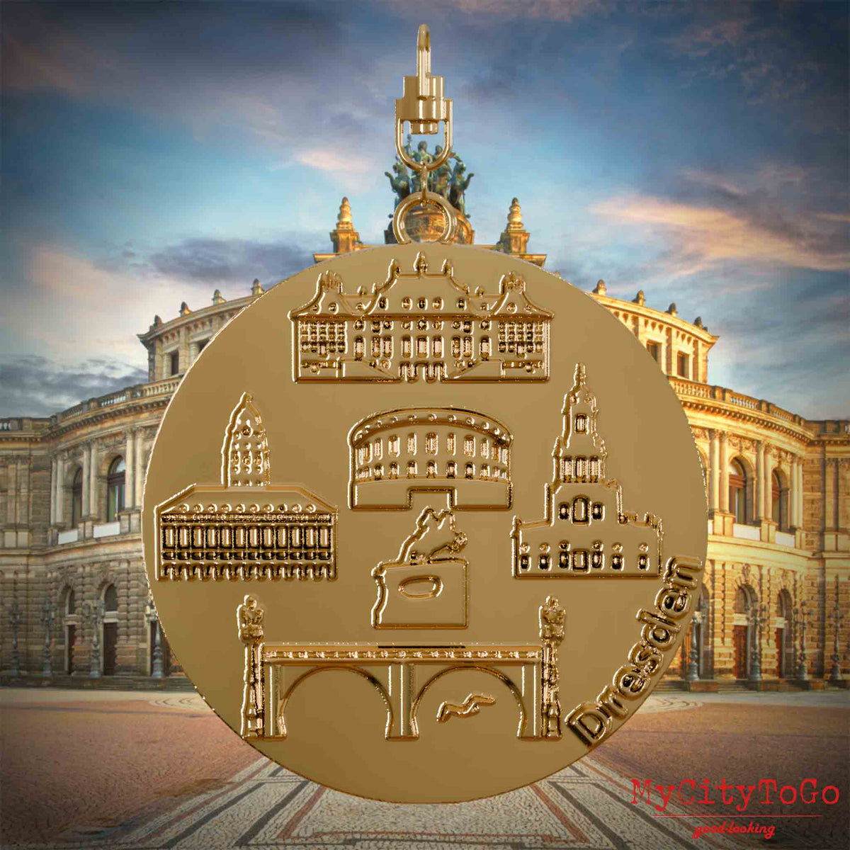 Halskette mit Drehwirbel und Vorderseite eines vergoldeten Schmuckanhängers, auf dem Reliefs bekannter Sehenswürdigkeiten der Stadt Dresden abgebildet sind. Den Hintergrund bildet eine Ansicht der Stadt Dresden.