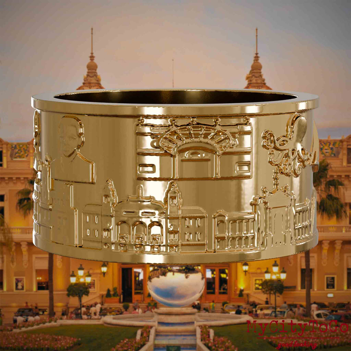 Vergoldeter Ring mit Reliefs bekannter Sehenswürdigkeiten der Stadt Monte Carlo. Den Hintergrund bildet eine Ansicht der Stadt Monte Carlo.