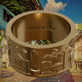 Ring aus vergoldetem Edelstahl mit Reliefs bekannter Sehenswürdigkeiten der Stadt Wuppertal und einer Gravur des Stadtnamens auf der Innenseite. Den Hintergrund bildet eine Ansicht  der Stadt Wuppertal.