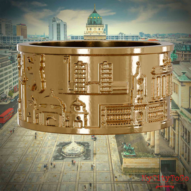 Vergoldeter Ring mit Reliefs bekannter Sehenswürdigkeiten der Stadt Berlin. Den Hintergrund bildet eine Ansicht der Stadt Berlin. 