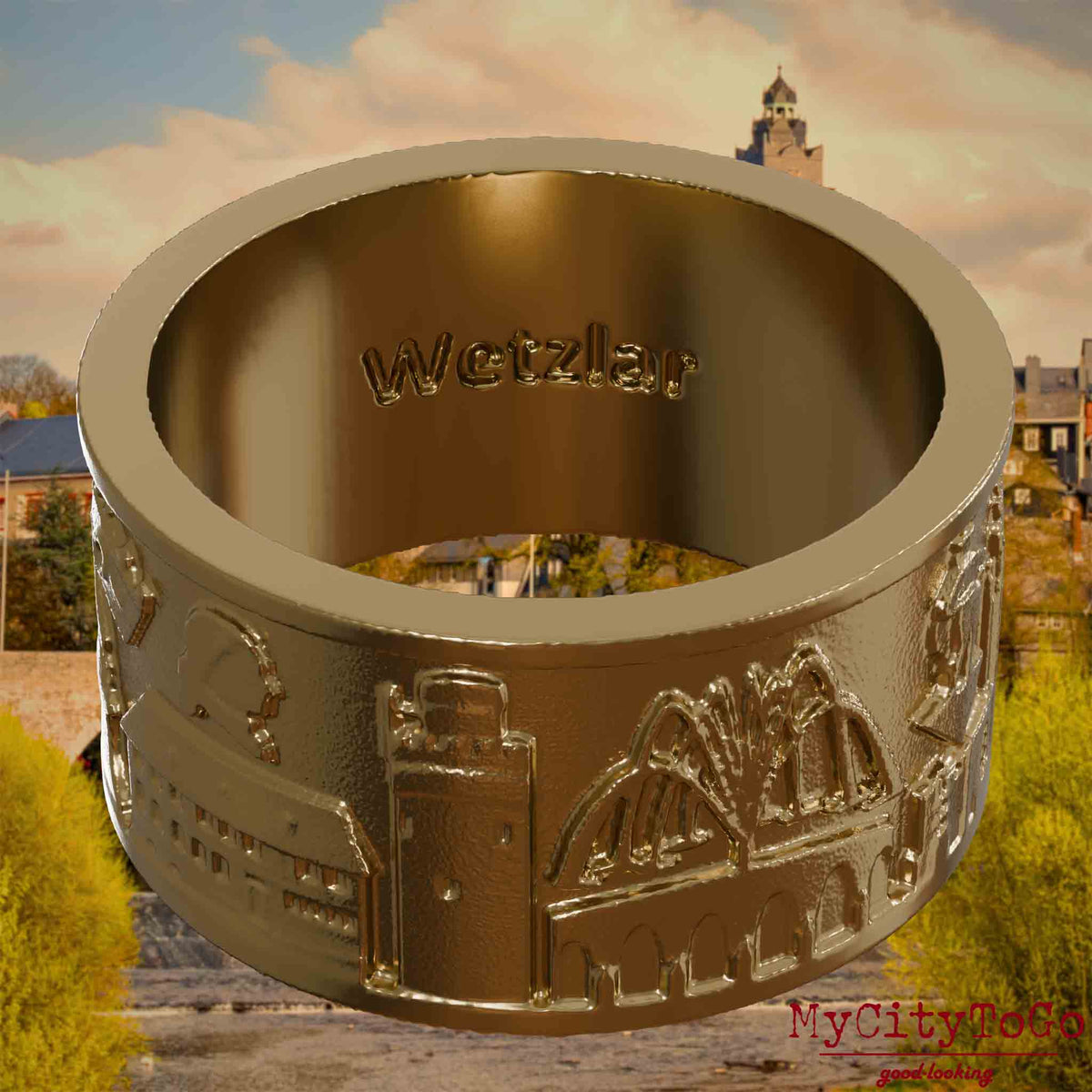 Ring aus vergoldetem Edelstahl mit Reliefs bekannter Sehenswürdigkeiten der Stadt Wetzlar und einer Gravur des Stadtnamens auf der Innenseite. Den Hintergrund bildet eine Ansicht der Stadt Wetzlar.