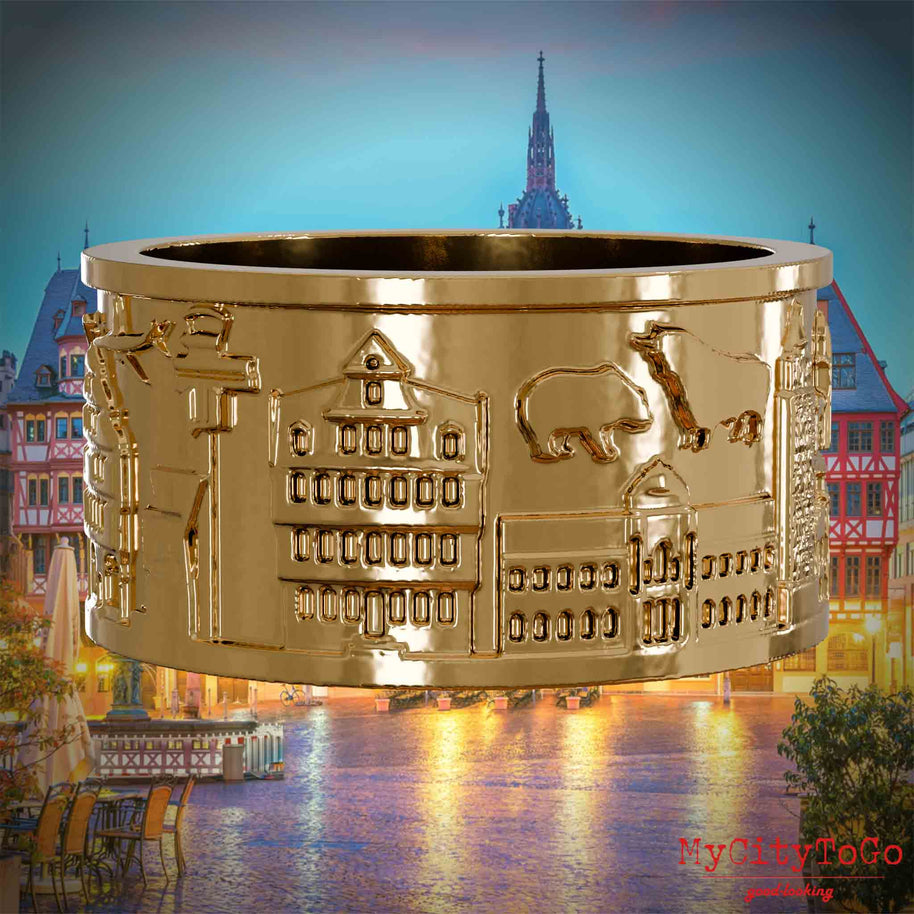 Vergoldeter Ring mit Reliefs bekannter Sehenswürdigkeiten der Stadt Frankfurt. Den Hintergrund bildet eine Ansicht der Stadt Frankfurt.