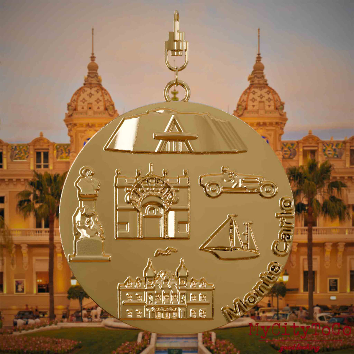Halskette mit Drehwirbel und Vorderseite eines vergoldeten Schmuckanhängers, auf dem Reliefs bekannter Sehenswürdigkeiten der Stadt Monte Carlo abgebildet sind. Den Hintergrund bildet eine Ansicht der Stadt Monte Carlo.
