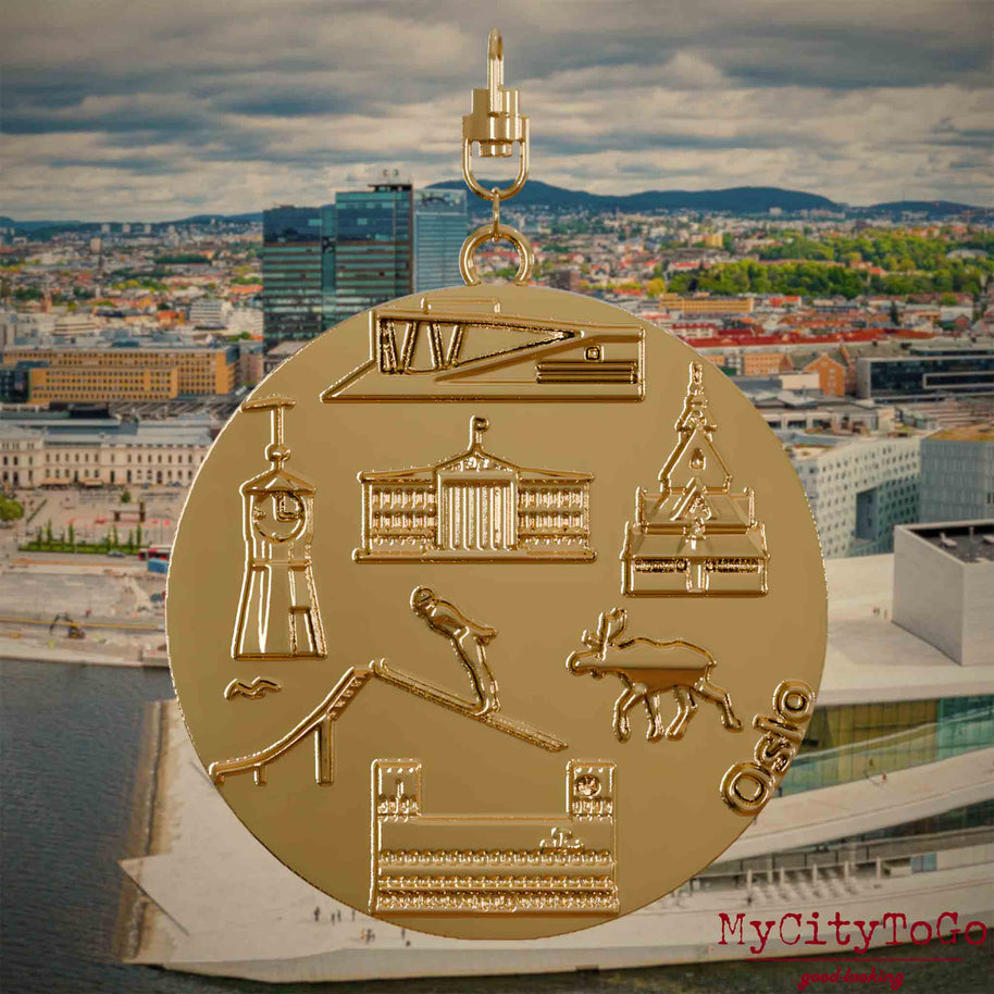 Halskette mit Drehwirbel und Vorderseite eines vergoldeten Schmuckanhängers, auf dem Reliefs bekannter Sehenswürdigkeiten der Stadt Oslo abgebildet sind. Den Hintergrund bildet eine Ansicht der Stadt Oslo.
