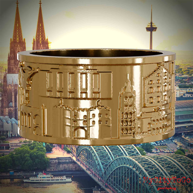 Vergoldeter Ring mit Reliefs bekannter Sehenswürdigkeiten der Stadt Koeln. Den Hintergrund bildet eine Ansicht der Stadt Koeln.