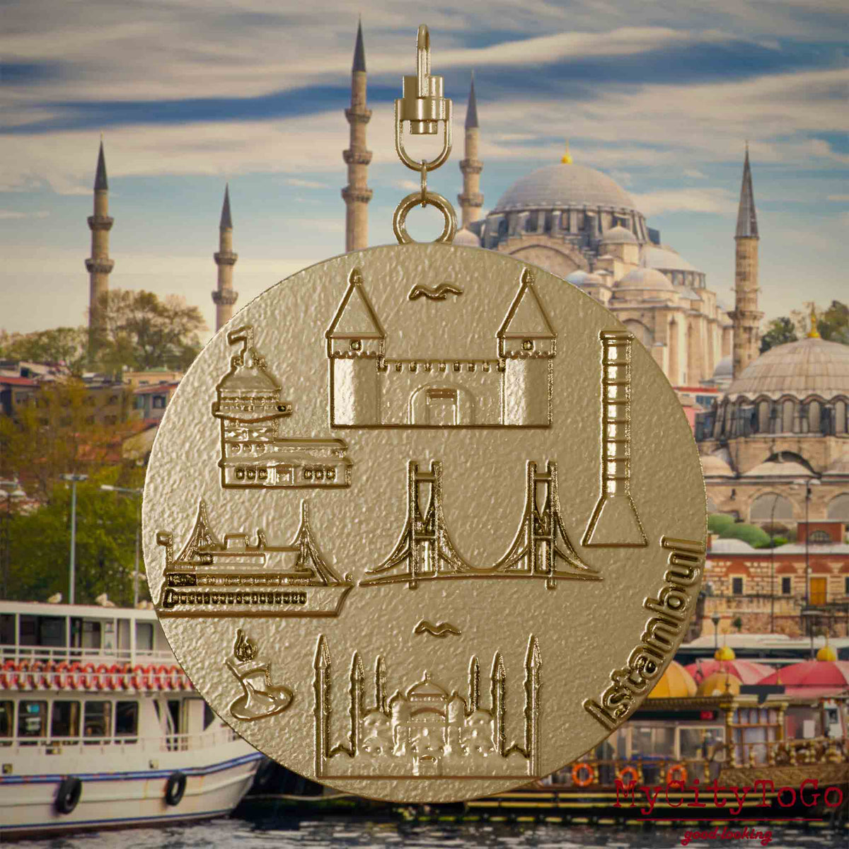 Halskette mit Drehwirbel und Vorderseite eines Schmuckanhängers aus vergoldetem Edelstahl, auf dem Reliefs bekannter Sehenswürdigkeiten der Stadt Istanbul abgebildet sind. Den Hintergrund bildet eine Ansicht der Stadt Istanbul.
