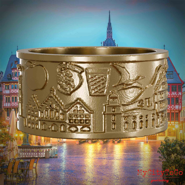Ring aus vergoldetem Edelstahl mit Reliefs bekannter Sehenswürdigkeiten der Stadt Frankfurt. Den Hintergrund bildet eine Ansicht der Stadt Frankfurt.