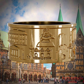 Vergoldeter Ring mit Reliefs bekannter Sehenswürdigkeiten der Stadt Bremen. Den Hintergrund bildet eine Ansicht der Stadt Bremen.
