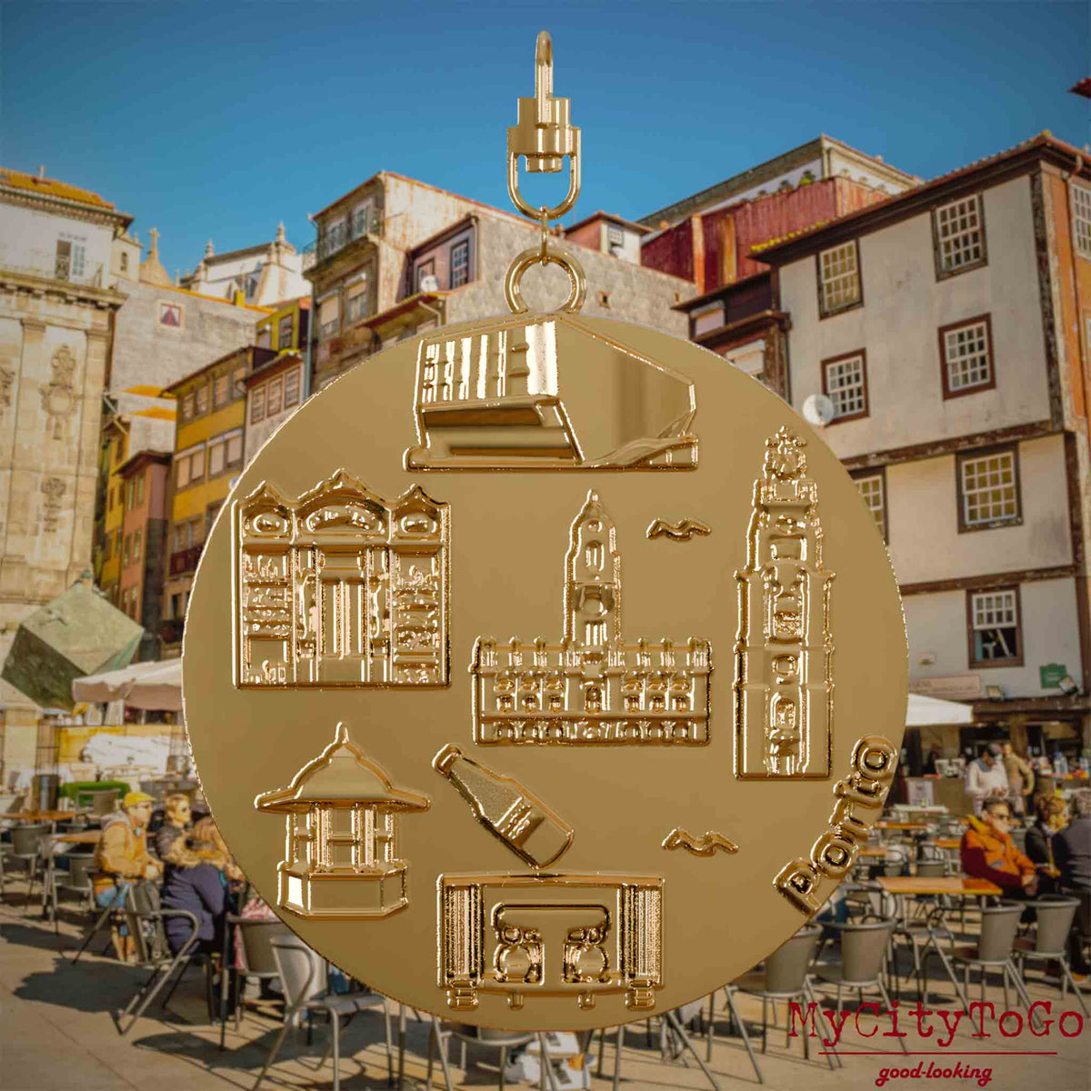 Halskette mit Drehwirbel und Vorderseite eines vergoldeten Schmuckanhängers, auf dem Reliefs bekannter Sehenswürdigkeiten der Stadt Porto abgebildet sind. Den Hintergrund bildet eine Ansicht der Stadt Porto.

