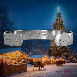 Innenseite eines silbernen Armreifs mit Reliefs weihnachtlicher Motive und der mehrsprachigen Gravur Frohe Weihnachten. Den Hintergrund bildet ein naechtliches Weihnachtsmotiv.