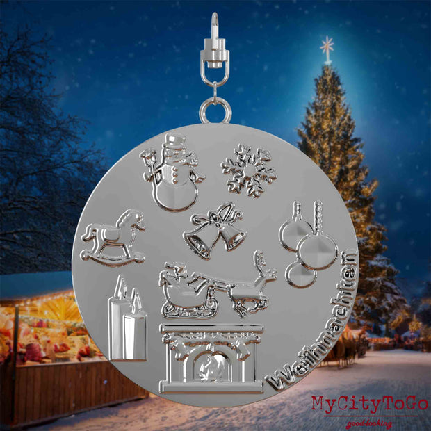 Halskette mit Drehwirbel und Vorderseite eines silbernen Schmuckanhängers, auf dem Reliefs bekannter Weihnachst- und Wintermotive abgebildet sind. Den Hintergrund bildet ein naechtliches Weihnachtsmotiv.